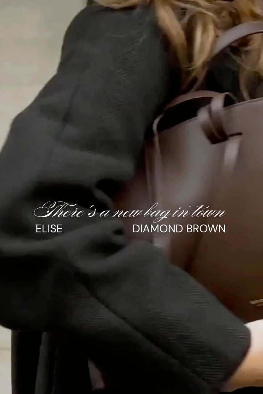 brown handbag worn under shoulder.